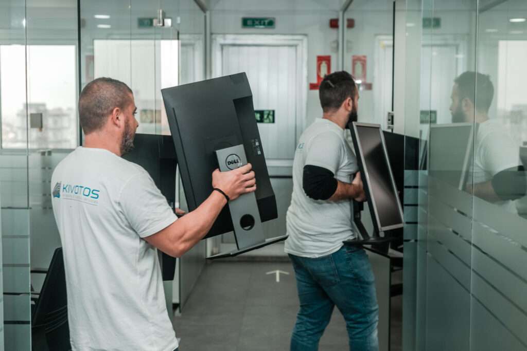 two men carrying computer screens